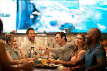 Group of adults at table with drinks and food